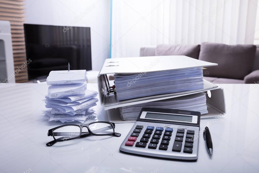 Close-up Of Folders With Receipts And Calculator On White Desk In Bedroom