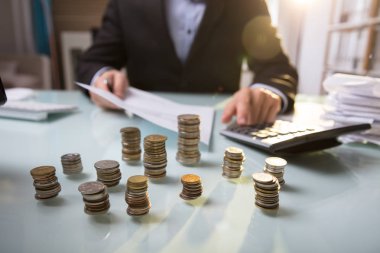 Belge üzerinde çalışmayı işadamı önünde yığılı sikke yakın çekim