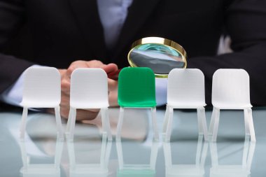 Bir işadamının'ın el Büyüteç aracılığıyla boş sandalye bakarak Close-Up