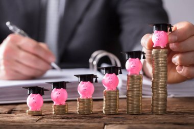 Piggybank mezuniyet kap ile artan yerleştirme işadamının'ın el sikkeler üzerinde ahşap Resepsiyon yığılmış.