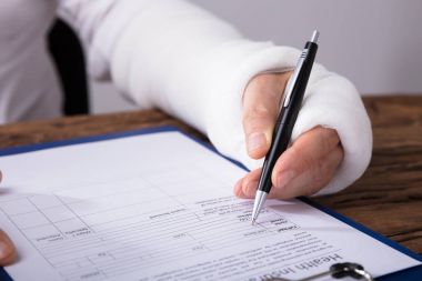 Bir işadamının kırık kol ahşap masa sağlık sigortası talep formu doldurma ile yakın çekim