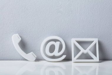 İletişim yöntemleri. Bir telefon, e-posta ve mesaj simgeleri beyaz duvara yaslanmış Close-Up