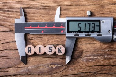 Ahşap arka plan üzerinde yükseltilmiş görünümü Risk metin blokları ve dijital elektronik Vernier Kaliper
