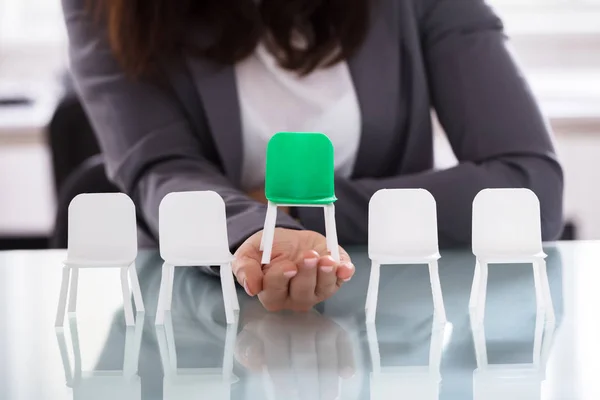 一个女商人的手 在一排白椅之间选择绿色椅的特写 — 图库照片