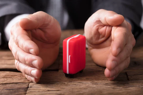 Close Businessperson Hand Holding Red Suitcase Wooden Desk — Stock Photo, Image