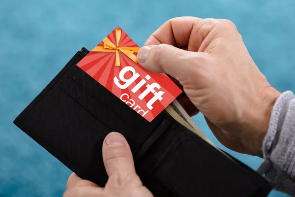 財布から赤いギフトカードを削除する人間の手のクローズアップ — ストック写真