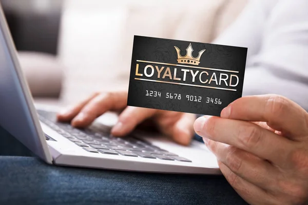 Close-up Of A Person\'s Hand With Loyalty Card Using Laptop