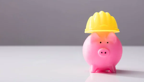 Zbliżenie Pink Piggy Bank Żółty Kask Biały Biurko — Zdjęcie stockowe