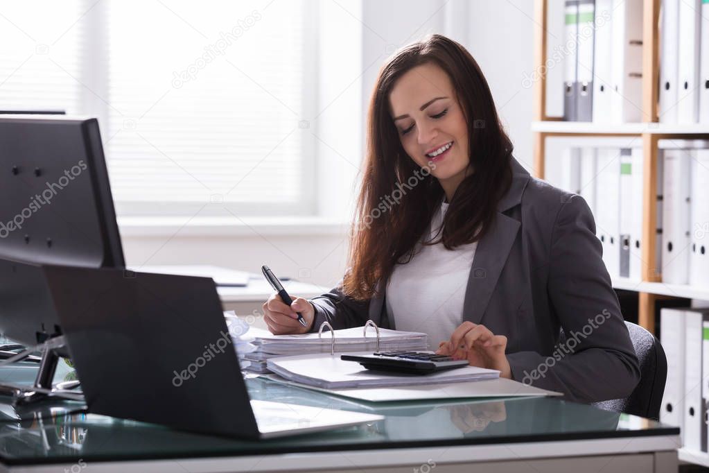 Happy Young Businesswoman Calculating Bill With Calculator