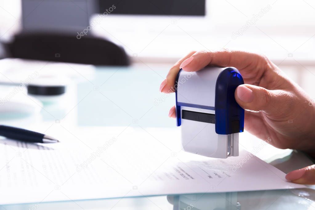 Close-up Of A Businessperson's Hand Stamping Document At Workplace