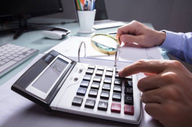 İşadamı'nın el büyüteç ile Bill denetlerken hesap makinesini kullanarak