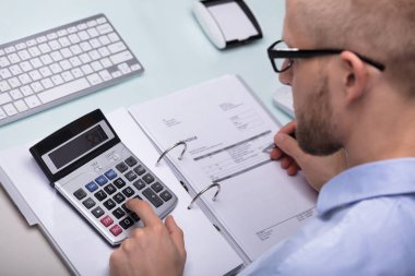 Fatura masasında hesaplamak için hesap makinesini kullanarak iş adamı