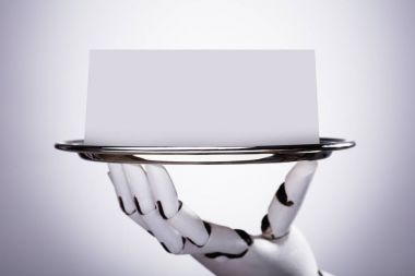 Plaka gri arka plan üzerinde boş kartı tutan Robotik el