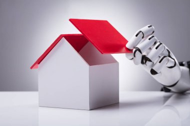 Gri arka planı kırmızı çatılı bir robot el bina konut Close-Up