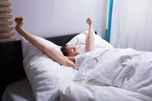 Jovem Mulher Acordando Esticando Mãos Cama — Fotografia de Stock