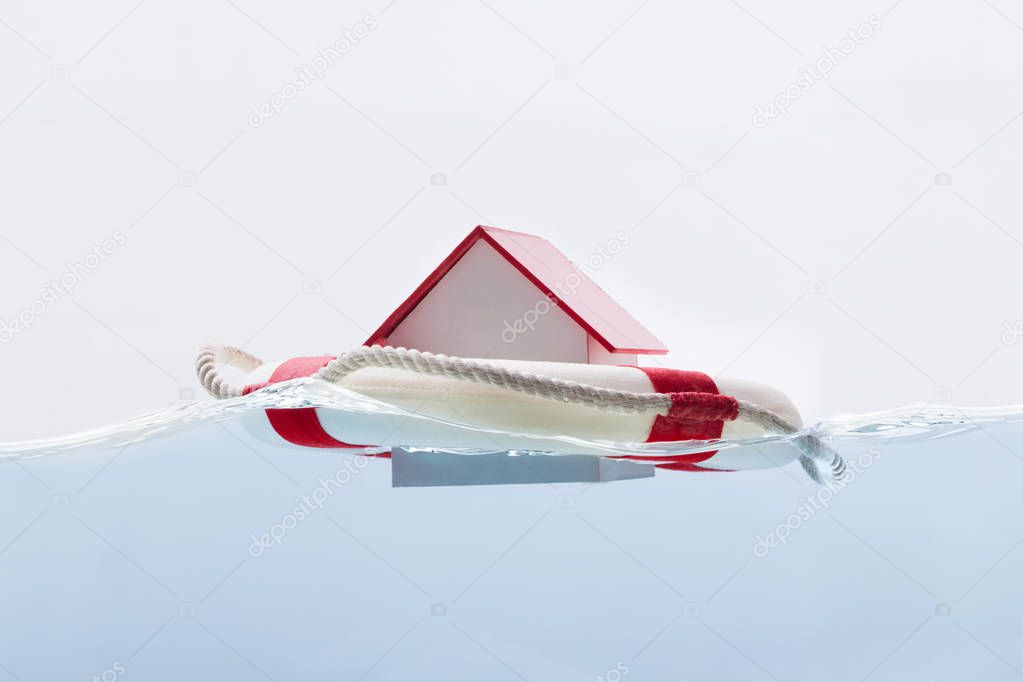 Close-up Of A House Floating On Lifebuoy Against White Background