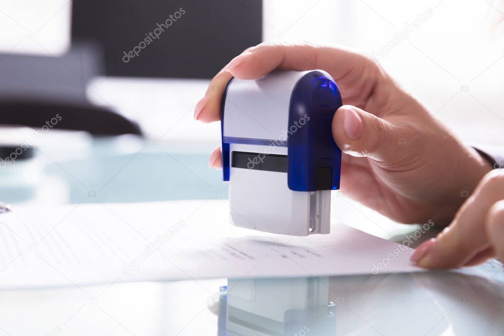 Close-up Of A Businessperson's Hand Stamping Document At Workplace