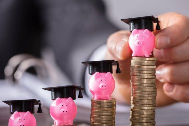 Piggybank mezuniyet kap ile artan yerleştirme işadamının'ın el sikkeler üzerinde ahşap Resepsiyon yığılmış.