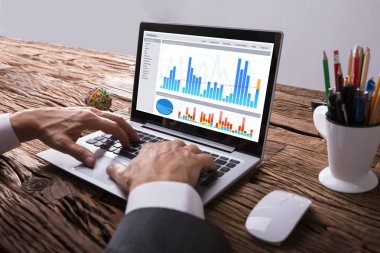 Grafik ile dizüstü bilgisayarda işyerinde çalışan bir işadamının'ın el Close-Up