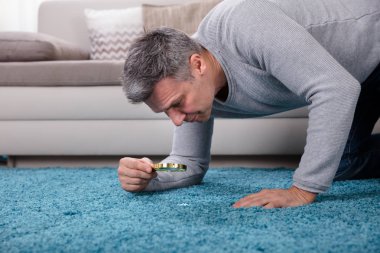 Mavi halı Büyüteç aracılığıyla bakarak bir olgun adam yan görünüm