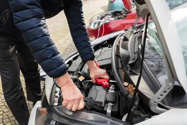ジャンパー ケーブルを使って車のバッテリを充電する人の手のクローズ アップ — ストック写真