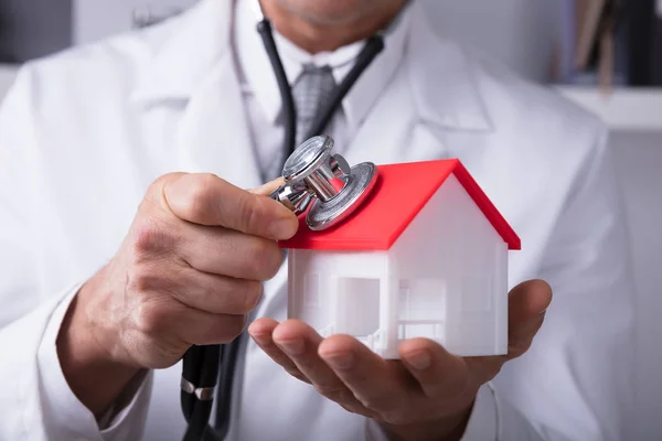 Close Mão Médico Segurando Estetoscópio Modelo Casa — Fotografia de Stock