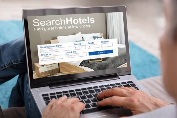 在笔记本电脑上搜索低价位的酒店手的特写 — 图库照片