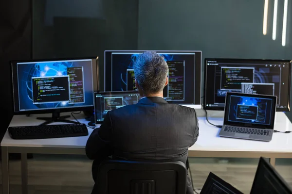 Rückansicht Eines Geschäftsmannes Der Büro Auf Mehrere Computerbildschirme Blickt — Stockfoto