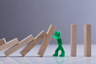 Yeşil bir insan figürü ahşap Dominos blok gri bir arka plana dayanır durdurma yan görünüm
