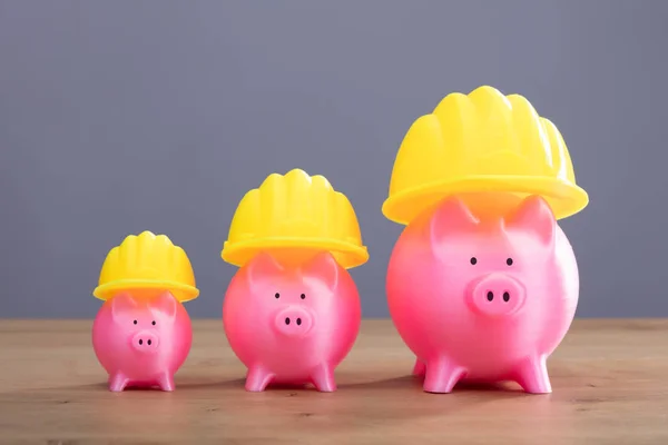 Close Van Toenemende Roze Piggy Banken Met Gele Helm Houten — Stockfoto