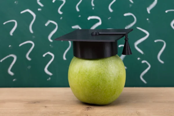Grönt Äpple Med Examen Hatt Framför Svarta Tavlan Visar Frågetecken — Stockfoto