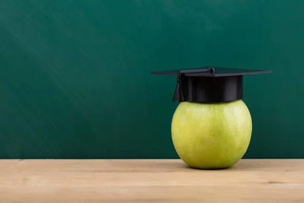 Primo Piano Una Mela Verde Con Cappello Laurea Sulla Scrivania — Foto Stock