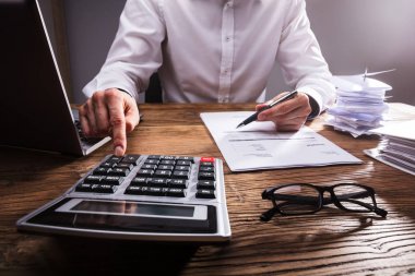 İşadamı'nın el ahşap masa hesap makinesiyle Bill hesaplama