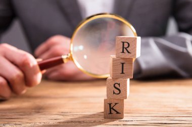 Büyüteç Camı tutan işadamı'nın el önündeki Risk sözcüğü ile ahşap bloklar Close-Up