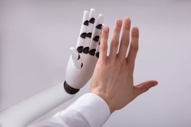 Robot ve gri arka plan üzerinde yüksek beş veren adam