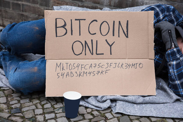 Beggar Sleeping On Street With Bitcoin Only Text On Cardboard