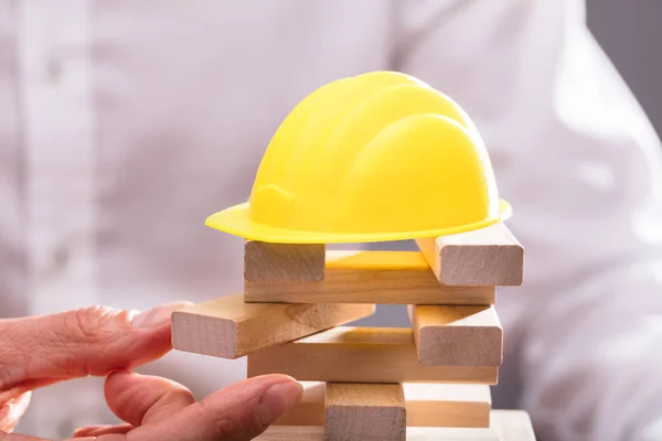 Gelber Bollenhut Über Der Hand Eines Geschäftsmannes Der Holzklötze Stapelt — Stockfoto