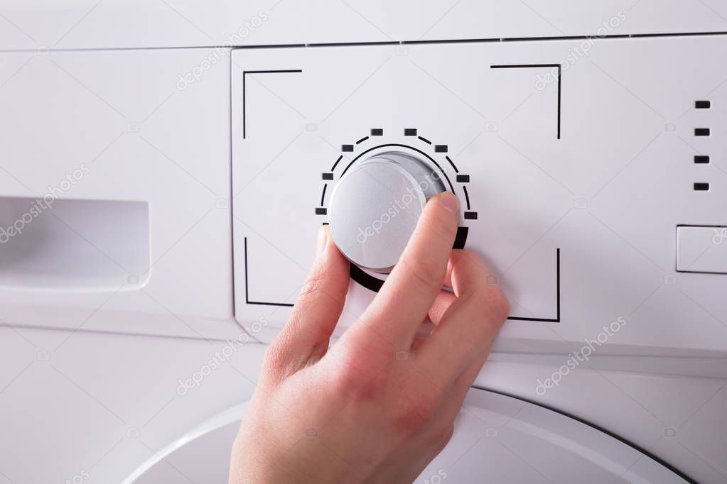 Close-up Of A Person's Hand Turning Button Of Washing Machine