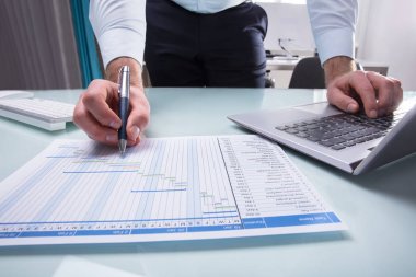 İşadamı'nın el dizüstü kullanarak Gantt grafiği üzerinde çalışma