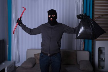 Plastik torba ve kollarını yükselterek levye tutan soyguncu yün içinde