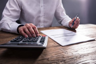 İşadamı'nın el ahşap masa hesap makinesiyle Bill hesaplama 