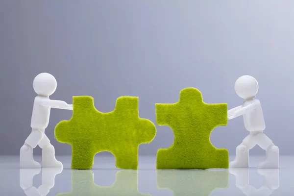 Seitenansicht Von Zwei Menschlichen Miniaturfiguren Beim Lösen Von Grünen Puzzles — Stockfoto