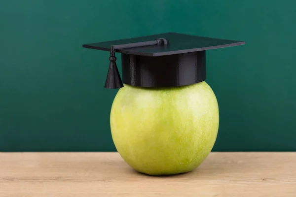 Primer Plano Una Manzana Verde Con Sombrero Graduación Escritorio Madera — Foto de Stock