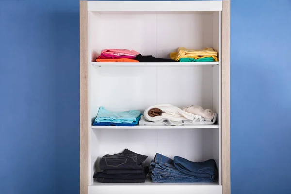 青い背景の棚に様々 な服のクローズ アップ — ストック写真