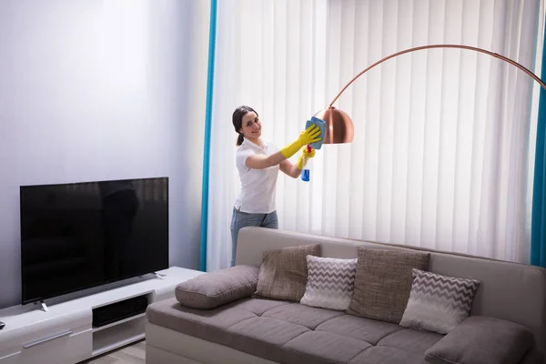 Jovem Zeladora Limpando Luz Elétrica Com Spray Casa — Fotografia de Stock