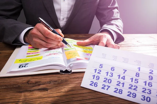 生意人的手检查日程表在日志与日历在木桌 — 图库照片