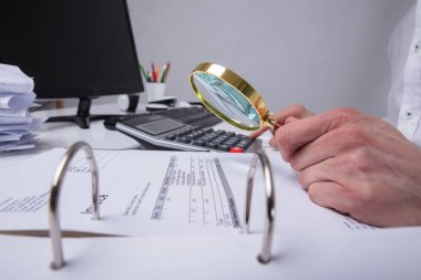 Fatura masa Büyüteç aracılığıyla inceleyerek bir işadamının'ın el Close-Up