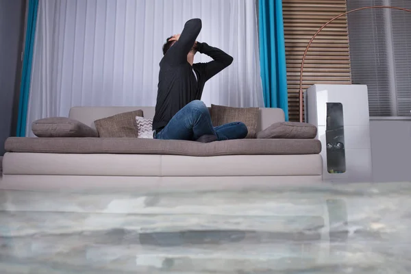 Lelaki Marah Pada Sofa Dengan Tangan Pada Kepala Kamar Banjir — Stok Foto