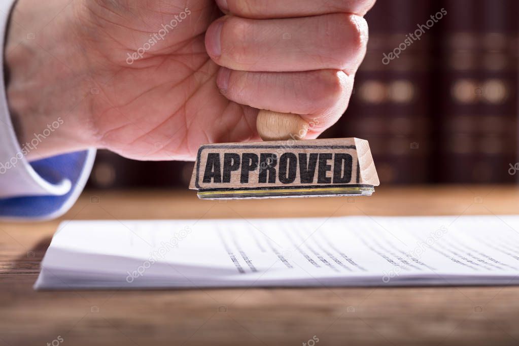 Close-up Of A Judge's Hand Approving Contract Form In Courtroom