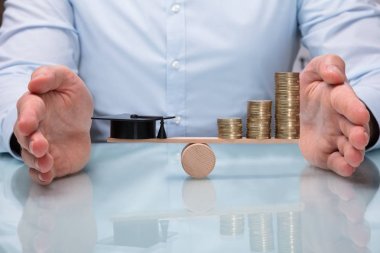 Mezuniyet şapka ve artan dengesini korumaya yardım Close-Up tahterevalli sikkelerinde yığılmış